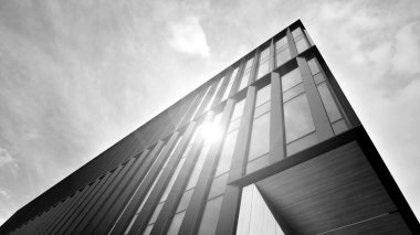 Glass modern building with sky background. Low angle view and architecture details. Urban abstract - windows of glass office building in  sunlight day. Black and white.