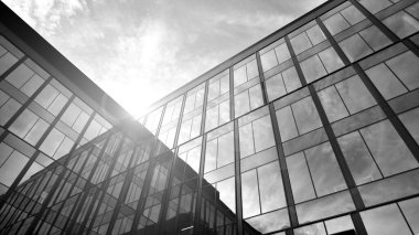 Glass modern building with sky background. Low angle view and architecture details. Urban abstract - windows of glass office building in  sunlight day. Black and white.
