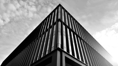 Glass modern building with sky background. Low angle view and architecture details. Urban abstract - windows of glass office building in  sunlight day. Black and white.