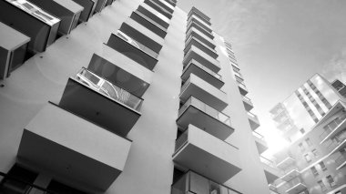The narrow passage between modern residential buildings. Walls of high-rise apartment buildings and a narrow strip of sky between them. Modern urban living districts. Bottom view. Black and white.