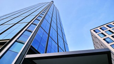 Mavi gökyüzüne karşı modern gökdelenlerin alt manzarası. Şehir merkezindeki iş binalarına bakıyorum..