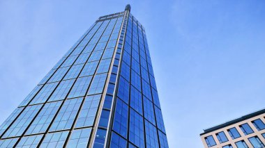 Mavi gökyüzüne karşı modern gökdelenlerin alt manzarası. Şehir merkezindeki iş binalarına bakıyorum..