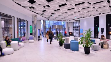 Varşova, Polonya. 8 Mart 2023. Alışveriş merkezinin önünden geçen insanlar. Alışveriş bölümü Varşova HUB. Geniş bir restoran ve mağaza yelpazesi var.. 