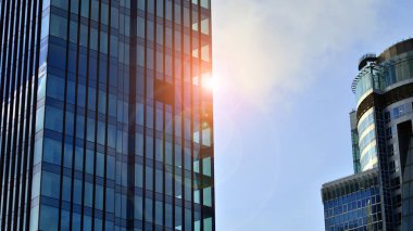 Şehir merkezindeki ticari binalara bakıyorum. Mavi gökyüzüne karşı modern ofis binası. Modern cam bir binanın pencereleri.