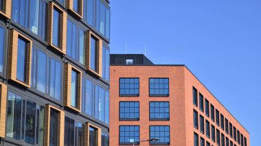 Şehirde modern bir şirket binası. Mavi gökyüzü binalara büyük cam pencerelere yansıyor. Cam cephe.