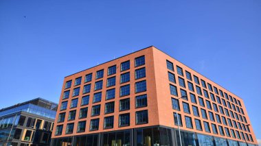 Şehirde modern bir şirket binası. Mavi gökyüzü binalara büyük cam pencerelere yansıyor. Cam cephe.