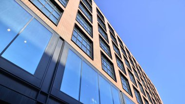 Şehirde modern bir şirket binası. Mavi gökyüzü binalara büyük cam pencerelere yansıyor. Cam cephe.