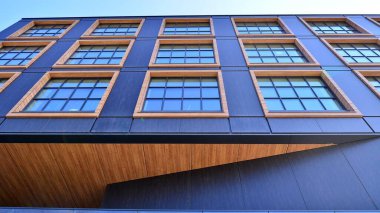 Şehirde modern bir şirket binası. Mavi gökyüzü binalara büyük cam pencerelere yansıyor. Cam cephe.