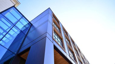 Şehirde modern bir şirket binası. Mavi gökyüzü binalara büyük cam pencerelere yansıyor. Cam cephe.