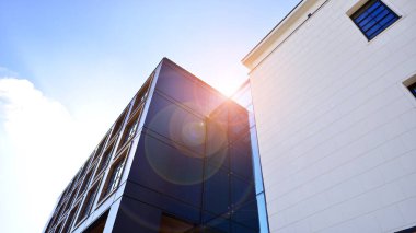 Şehirde modern bir şirket binası. Mavi gökyüzü binalara büyük cam pencerelere yansıyor. Cam cephe.