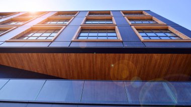 Şehirde modern bir şirket binası. Mavi gökyüzü binalara büyük cam pencerelere yansıyor. Cam cephe.