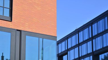 Şehirde modern bir şirket binası. Mavi gökyüzü binalara büyük cam pencerelere yansıyor. Cam cephe.