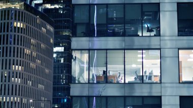 Ofis binalarının pencereleri gece aydınlandı. Cam mimari, geceleri şirket binası, iş konsepti. Mavi grafik filtresi.