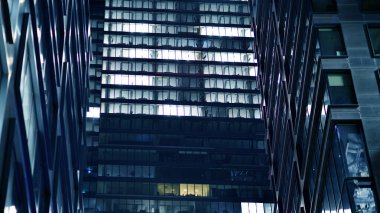 Ofis binalarının pencereleri gece aydınlandı. Cam mimari, geceleri şirket binası, iş konsepti. Mavi grafik filtresi.