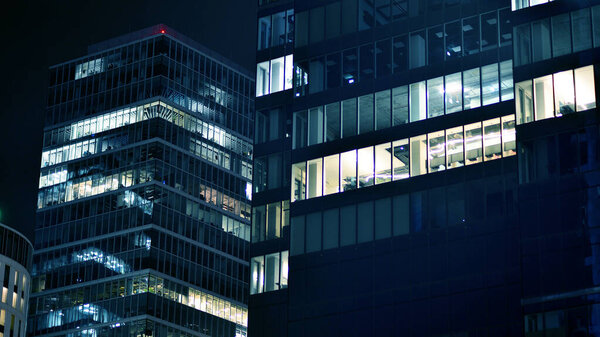 Pattern of office buildings windows illuminated at night. Glass architecture ,corporate building at night - business concept. Blue graphic filter.