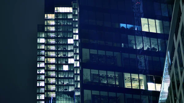 办公大楼的窗户在夜间照明 玻璃建筑 公司建筑在夜间营业的概念 蓝色图形滤波器 — 图库照片