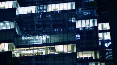 Ofis binalarının pencereleri gece aydınlandı. Cam mimari, geceleri şirket binası, iş konsepti. Mavi grafik filtresi.