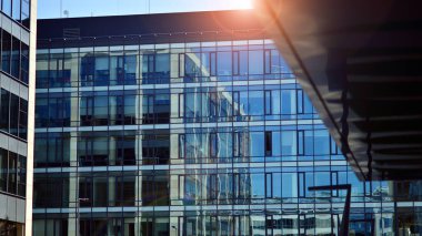 Çağdaş mimarinin soyut bir parçası, camdan ve betondan yapılmış duvarlar. Yansıtıcı camla kaplı modern bir binanın cam kaplamalı dış cephesinin soyut yakın çekimi..