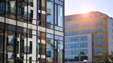 Çağdaş mimarinin soyut bir parçası, camdan ve betondan yapılmış duvarlar. Yansıtıcı camla kaplı modern bir binanın cam kaplamalı dış cephesinin soyut yakın çekimi..