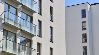 Mavi gökyüzü olan güneşli bir günde modern apartman binaları. Modern bir apartmanın ön cephesi. Gündüz gözüyle çağdaş yerleşim yerinin dış tarafında.. 