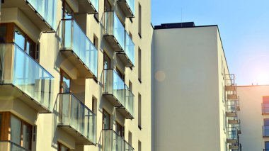 Mavi gökyüzü olan güneşli bir günde modern apartman binaları. Modern bir apartmanın ön cephesi. Gündüz gözüyle çağdaş yerleşim yerinin dış tarafında.. 