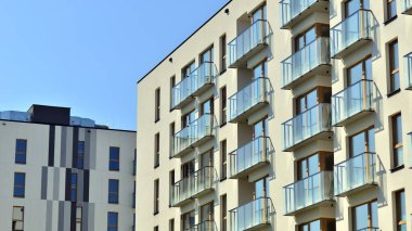 Mavi gökyüzü olan güneşli bir günde modern apartman binaları. Modern bir apartmanın ön cephesi. Gündüz gözüyle çağdaş yerleşim yerinin dış tarafında.. 