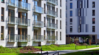 Mavi gökyüzü olan güneşli bir günde modern apartman binaları. Modern bir apartmanın ön cephesi. Gündüz gözüyle çağdaş yerleşim yerinin dış tarafında.. 