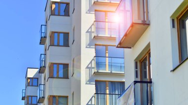 Mavi gökyüzü olan güneşli bir günde modern apartman binaları. Modern bir apartmanın ön cephesi. Gündüz gözüyle çağdaş yerleşim yerinin dış tarafında.. 