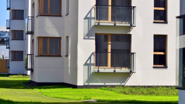 Mavi gökyüzü olan güneşli bir günde modern apartman binaları. Modern bir apartmanın ön cephesi. Gündüz gözüyle çağdaş yerleşim yerinin dış tarafında.. 