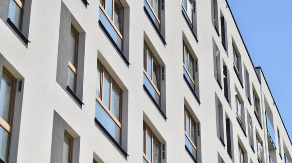 Современные жилые дома в солнечный день с голубым небом. Фасад современного многоквартирного дома. Внешний вид современного жилого здания при дневном свете. 