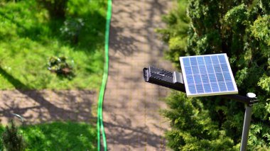 Işıklandırma direği, fotovoltaik panel ve yeşil arka planlı LED lamba ışıkları. Yenilenebilir enerji konsepti üretimi.