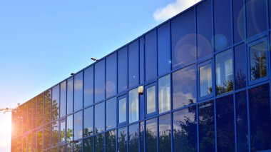 Çağdaş mimarinin soyut bir parçası, camdan ve betondan yapılmış duvarlar. Yansıtıcı camla kaplı modern bir binanın cam kaplamalı dış cephesinin soyut yakın çekimi..