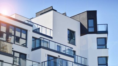 Parlak yüzlü apartman dairesi. Bir sürü kare cam pencere ve balkonu olan modern minimalist mimari.