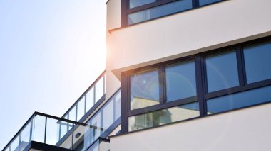 Parlak yüzlü apartman dairesi. Bir sürü kare cam pencere ve balkonu olan modern minimalist mimari.