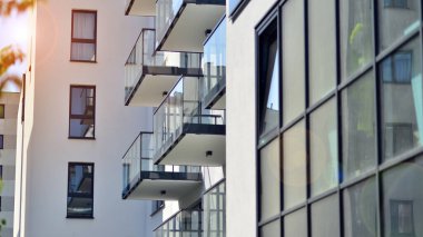 Parlak yüzlü apartman dairesi. Bir sürü kare cam pencere ve balkonu olan modern minimalist mimari.