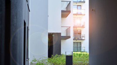 Parlak yüzlü apartman dairesi. Bir sürü kare cam pencere ve balkonu olan modern minimalist mimari.