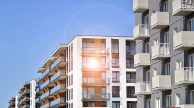 Parlak yüzlü apartman dairesi. Bir sürü kare cam pencere ve balkonu olan modern minimalist mimari.