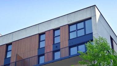 Çevre mimarisi. Yeşil ağaç ve yeni apartman. Doğanın ve modernliğin ahengi. Yeşil yerleşim bölgesinde yeni daireleri olan modern bir yerleşim yeri.. 