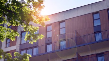 Çevre mimarisi. Yeşil ağaç ve yeni apartman. Doğanın ve modernliğin ahengi. Yeşil yerleşim bölgesinde yeni daireleri olan modern bir yerleşim yeri.. 