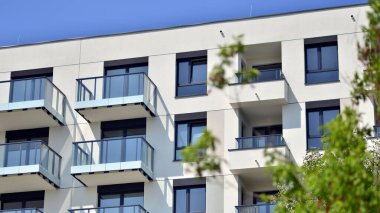 Çevre mimarisi. Yeşil ağaç ve yeni apartman. Doğanın ve modernliğin ahengi. Yeşil yerleşim bölgesinde yeni daireleri olan modern bir yerleşim yeri.. 