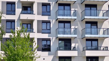 Çevre mimarisi. Yeşil ağaç ve yeni apartman. Doğanın ve modernliğin ahengi. Yeşil yerleşim bölgesinde yeni daireleri olan modern bir yerleşim yeri.. 