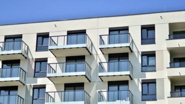 Parlak yüzlü apartman dairesi. Bir sürü kare cam pencere ve balkonu olan modern minimalist mimari.