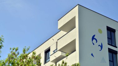 Çevre mimarisi. Yeşil ağaç ve yeni apartman. Doğanın ve modernliğin ahengi. Yeşil yerleşim bölgesinde yeni daireleri olan modern bir yerleşim yeri.. 