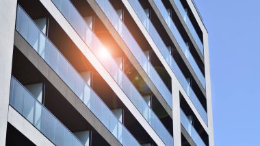 Parlak yüzlü apartman dairesi. Bir sürü kare cam pencere ve balkonu olan modern minimalist mimari.