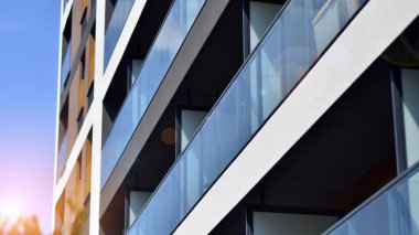 Parlak yüzlü apartman dairesi. Bir sürü kare cam pencere ve balkonu olan modern minimalist mimari.