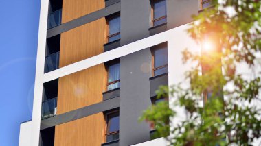 Çevre mimarisi. Yeşil ağaç ve yeni apartman. Doğanın ve modernliğin ahengi. Yeşil yerleşim bölgesinde yeni daireleri olan modern bir yerleşim yeri.. 