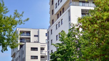 Çevre mimarisi. Yeşil ağaç ve yeni apartman. Doğanın ve modernliğin ahengi. Yeşil yerleşim bölgesinde yeni daireleri olan modern bir yerleşim yeri.. 