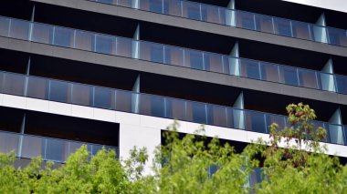 Çevre mimarisi. Yeşil ağaç ve yeni apartman. Doğanın ve modernliğin ahengi. Yeşil yerleşim bölgesinde yeni daireleri olan modern bir yerleşim yeri.. 