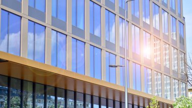 Yansıtıcı camlarla kaplı modern bir binanın cam kaplamalı dış cephesinin soyut yakın çekimi. Mimari soyut arkaplan. Cam duvar ve ön cephe ayrıntıları.