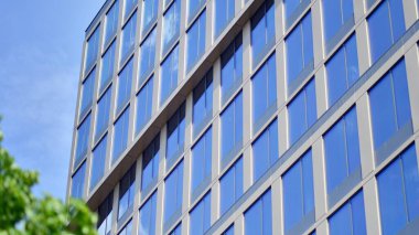 Yansıtıcı camlarla kaplı modern bir binanın cam kaplamalı dış cephesinin soyut yakın çekimi. Mimari soyut arkaplan. Cam duvar ve ön cephe ayrıntıları.